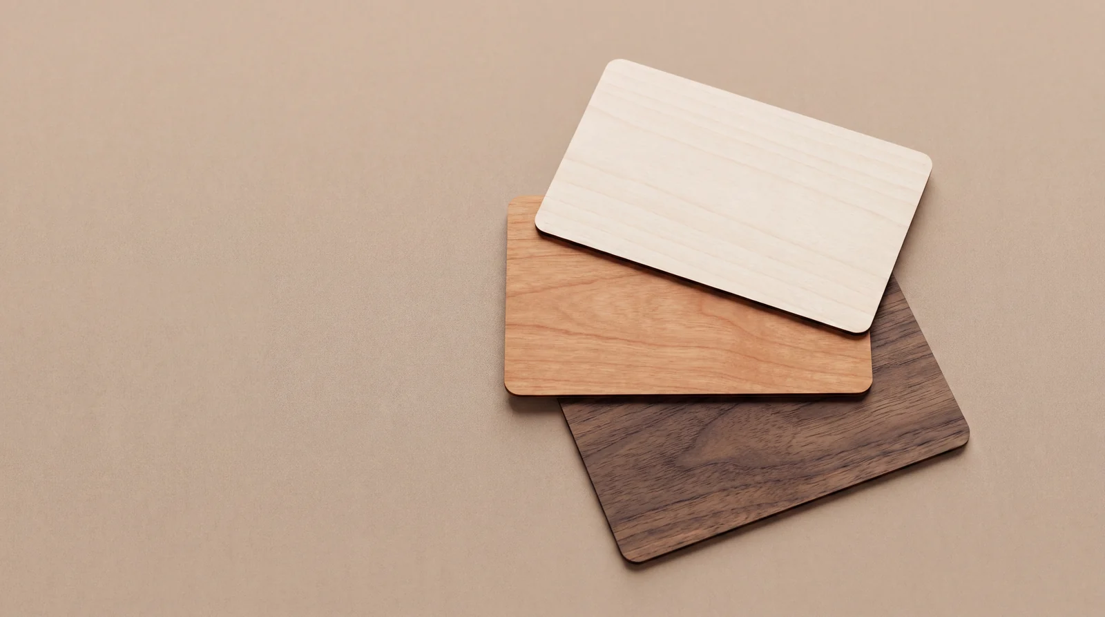 Three blank wooden hotel key cards in different species, showing the range of grain and tone
