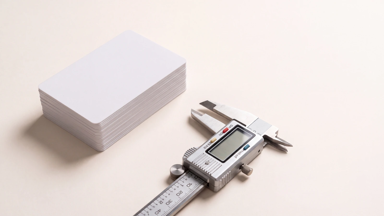 Stack of plastic cards measured with a caliper to show card thickness