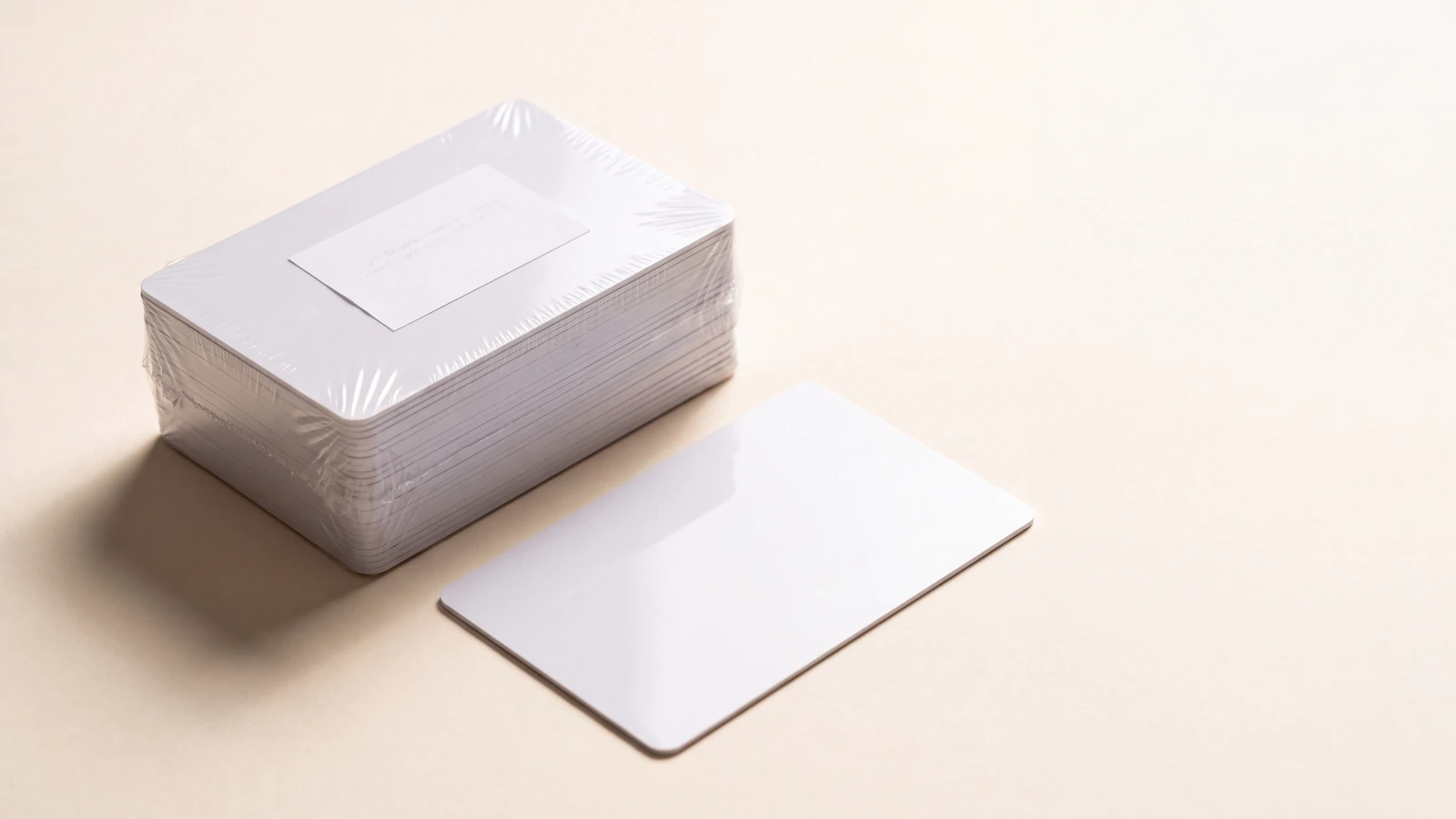 Shrink-wrapped stack of blank plastic cards with a batch slip beside a single loose card