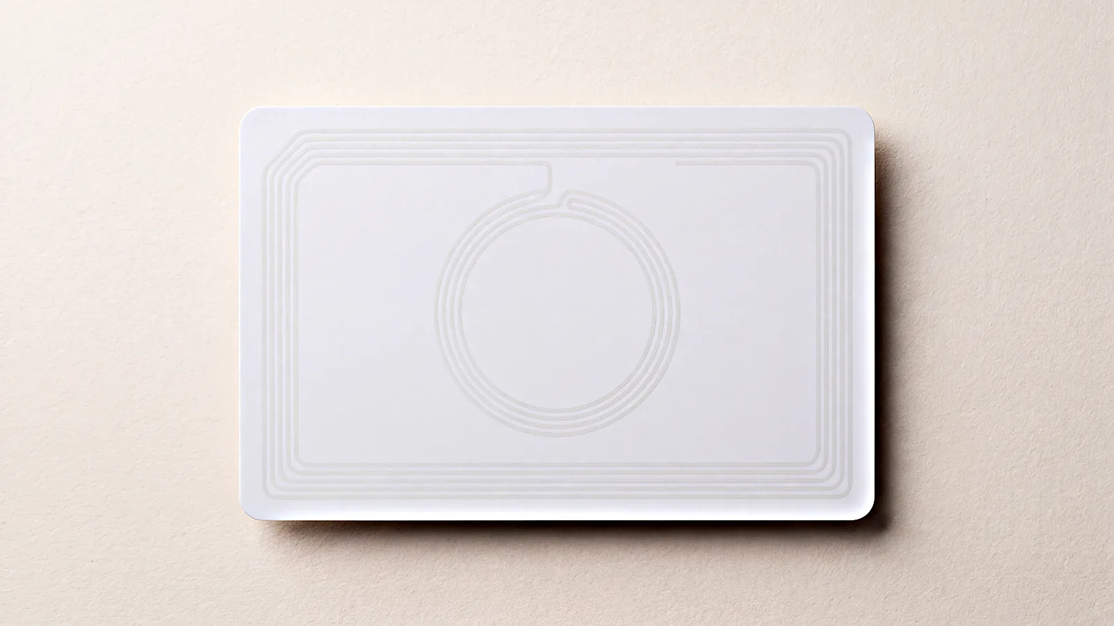 A blank white card seen from above with two faint antenna coils visible beneath the surface