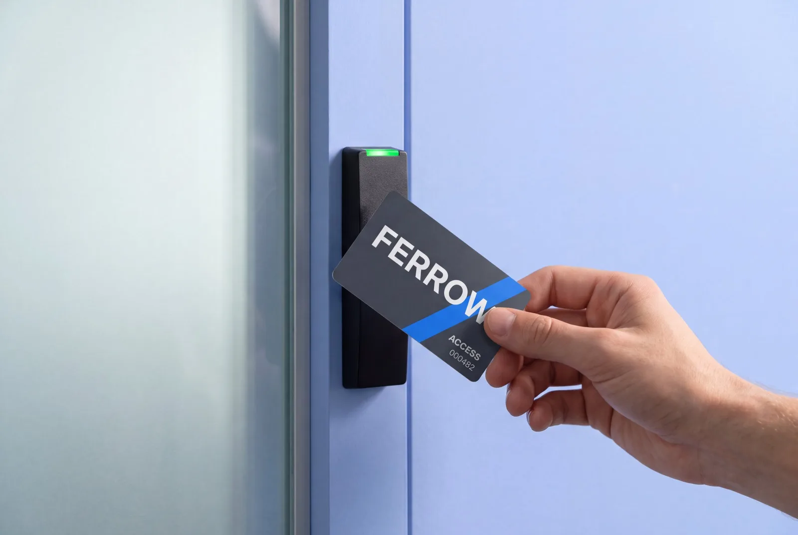 Hand holding a printed 125 kHz proximity card with an ID number at a wall access reader next to a glass door