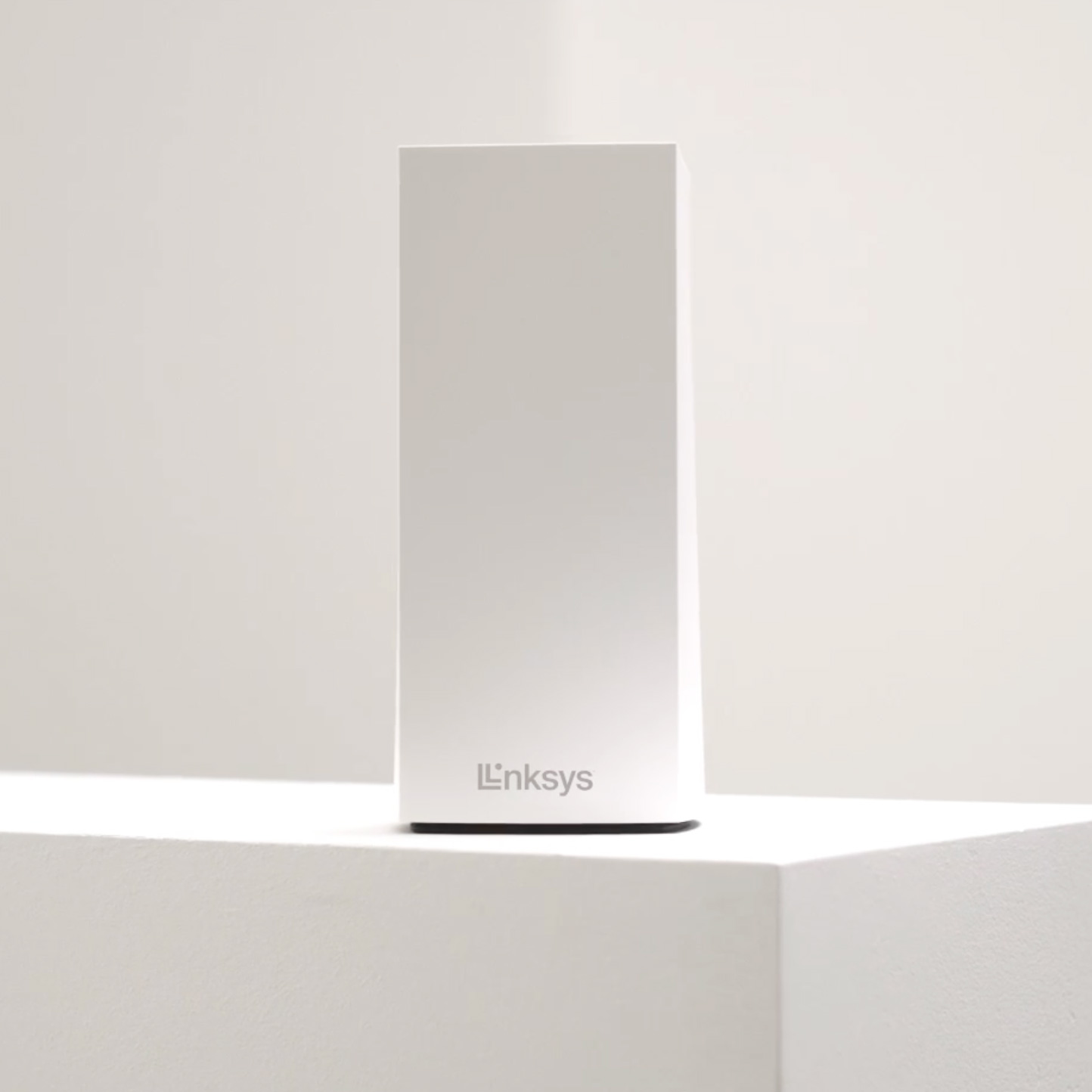 Vertical white Linksys wireless router placed on a white pedestal against a plain light background.