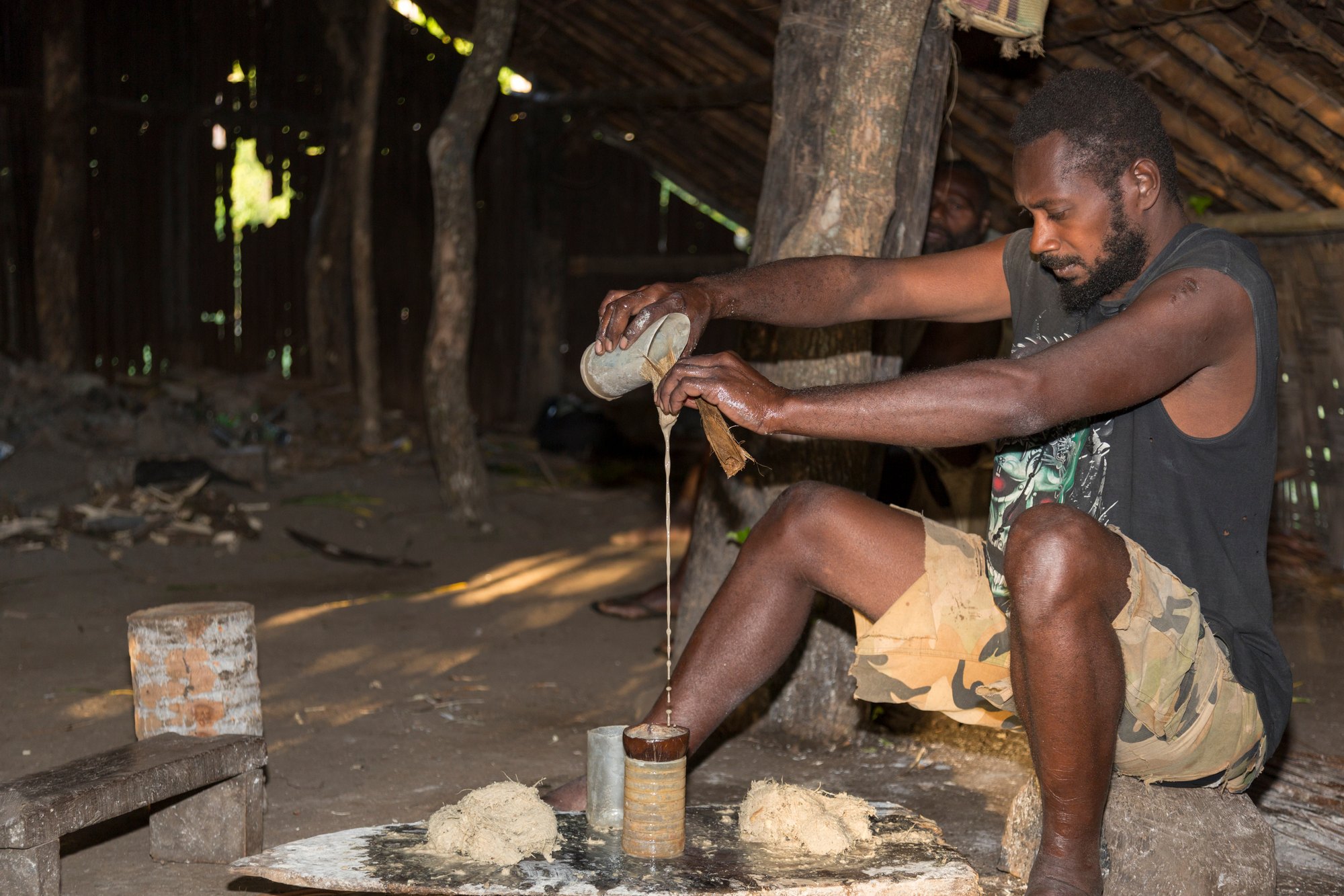 Hands preparing kava in a traditional bowl