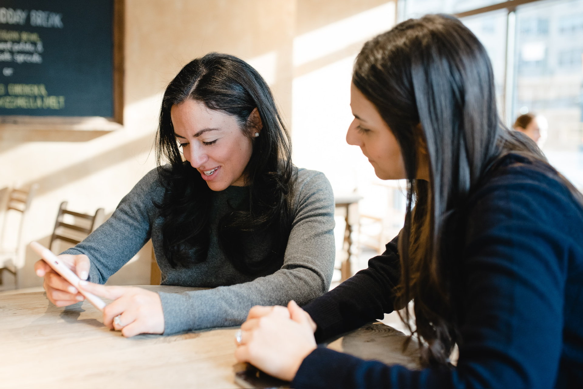 Two founders looking at the same screen across a cafe table