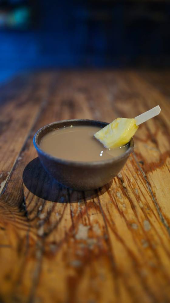 A shell of kava served on the bar with a pineapple garnish