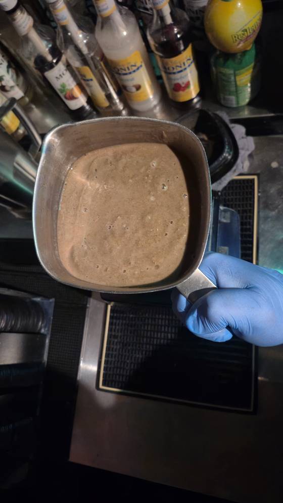 The 12 oz service ladle holding freshly stirred kava, showing suspended particulate