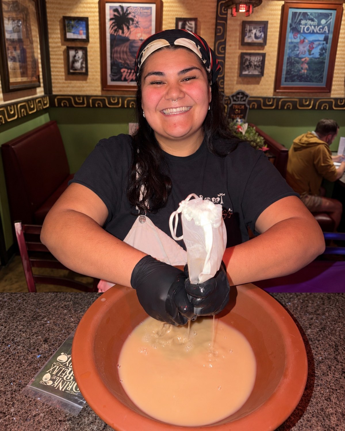Nick Norges and Sili Vuki, managers at Root of Happiness Kava Bars, hand-squeezing kava through nylon strainer bags