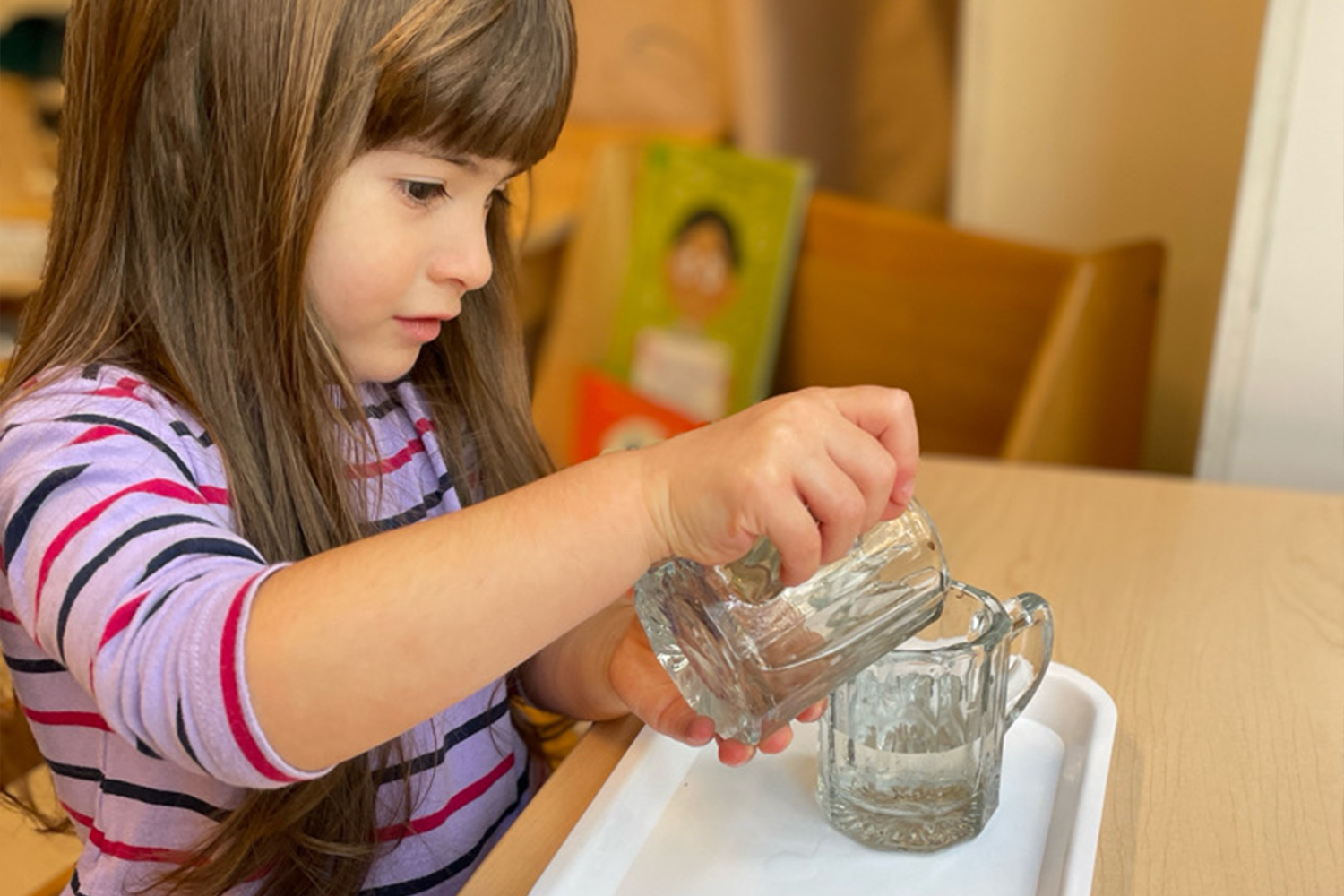 Battery Park Montessori student focused on pouring water