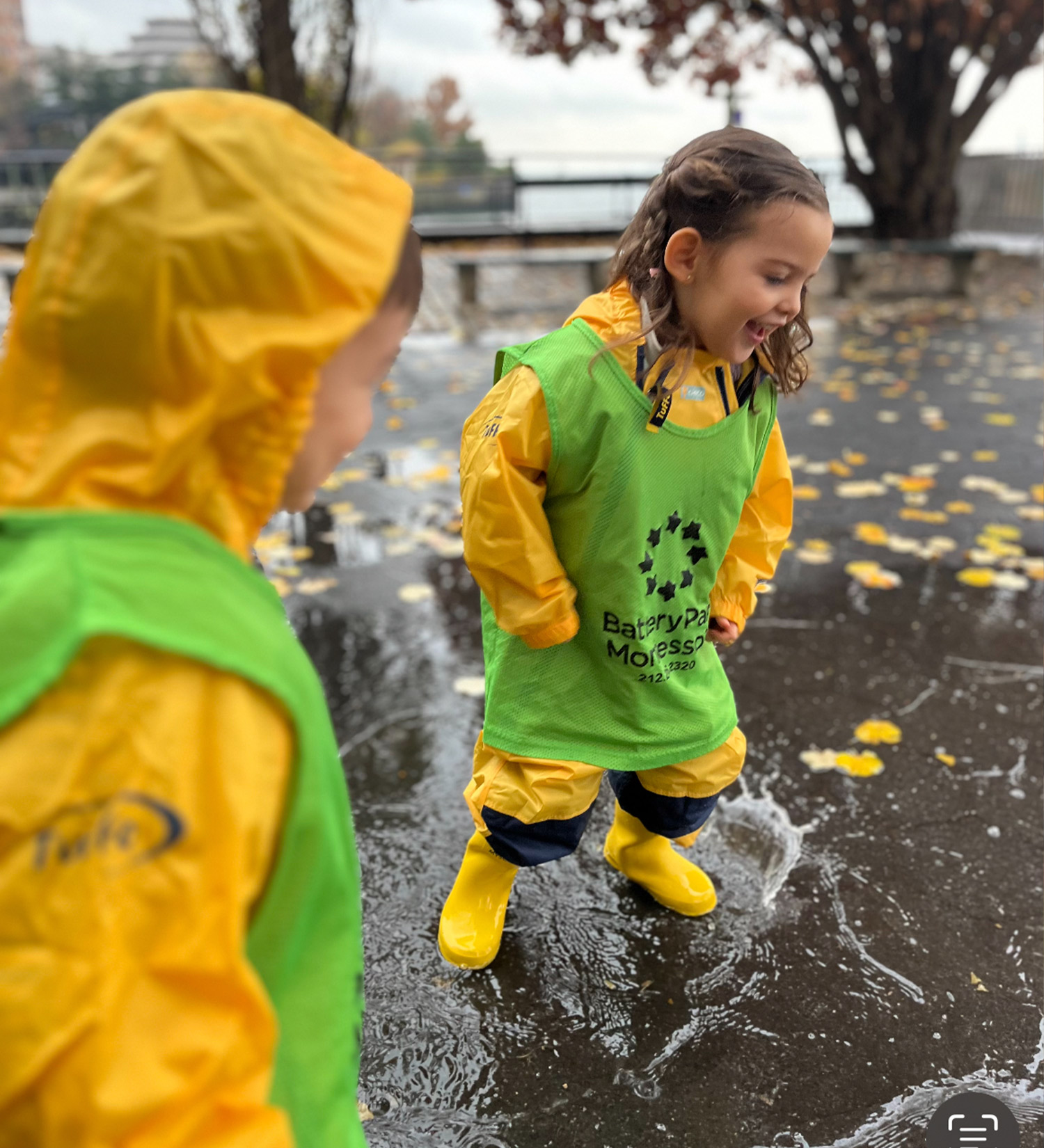Students playing outdoors on a rainy day and jumping in puddles