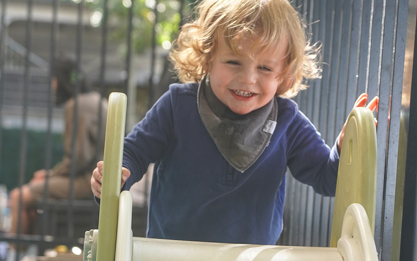 Nursery student climbs to the top of the slide in our outdoor patio.