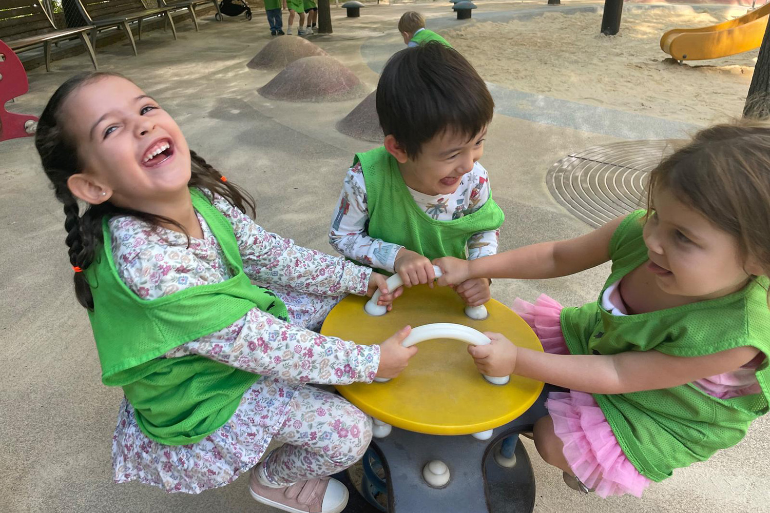 Three students spinning in circles at the playground