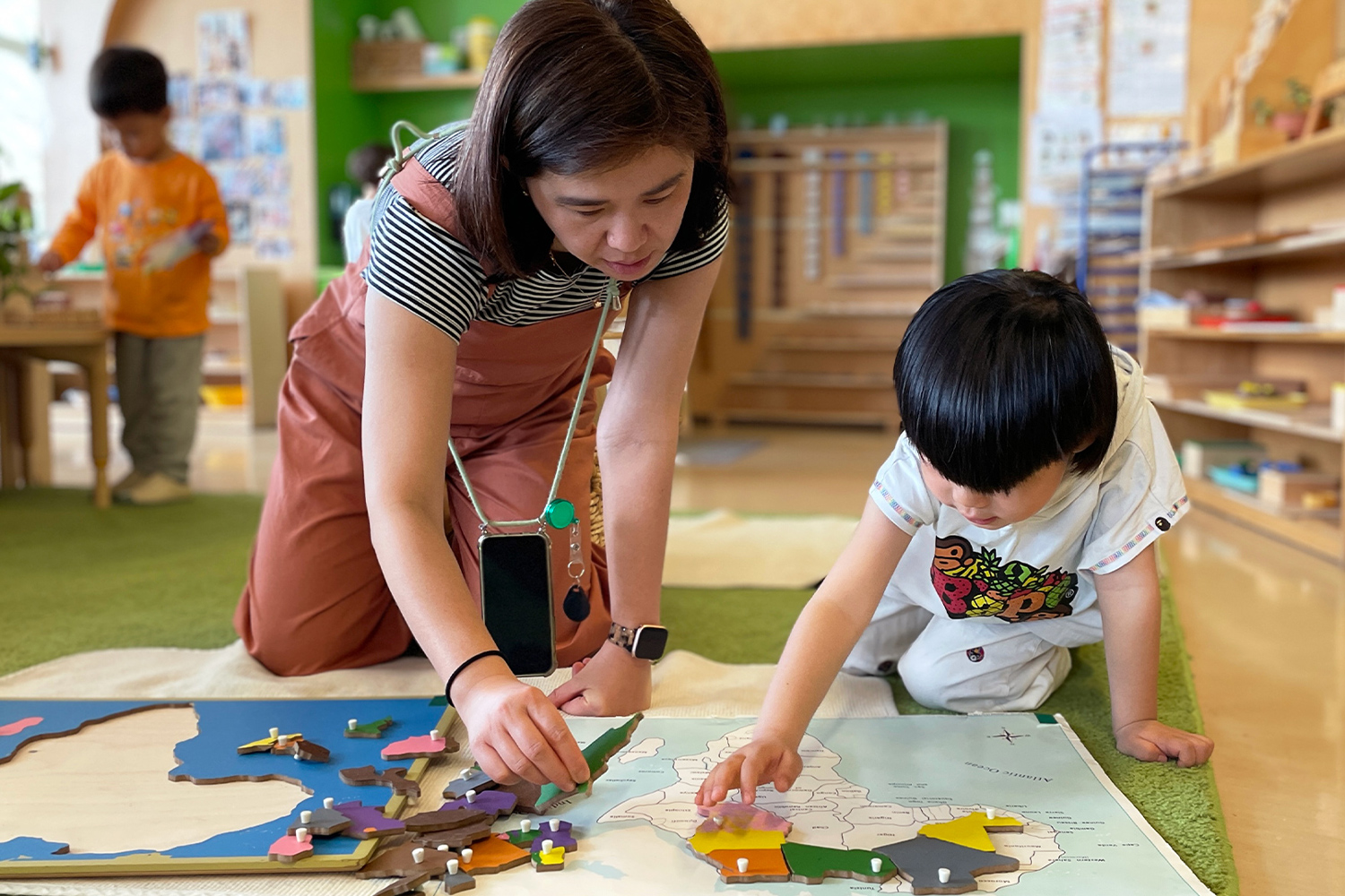 Student and teacher work together on map puzzle in the classroom at Battery Park Montessori