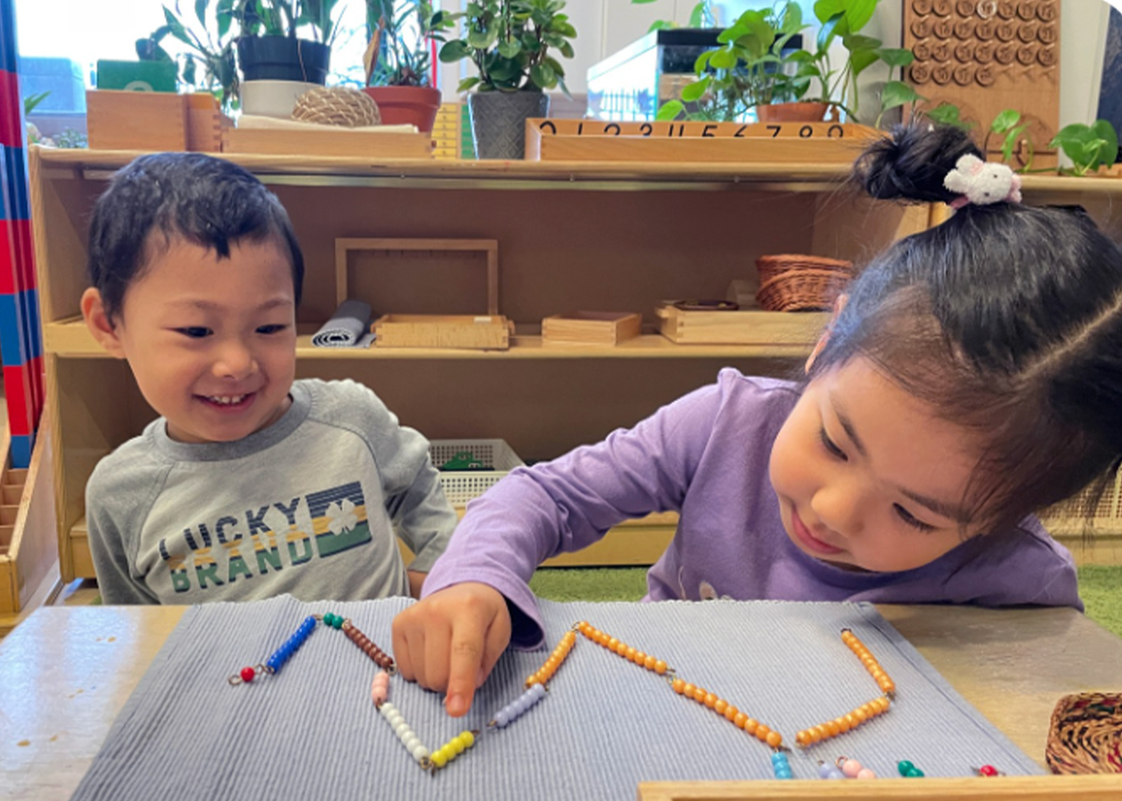 Two students laughing and having fun while working together on Montessori counting beads