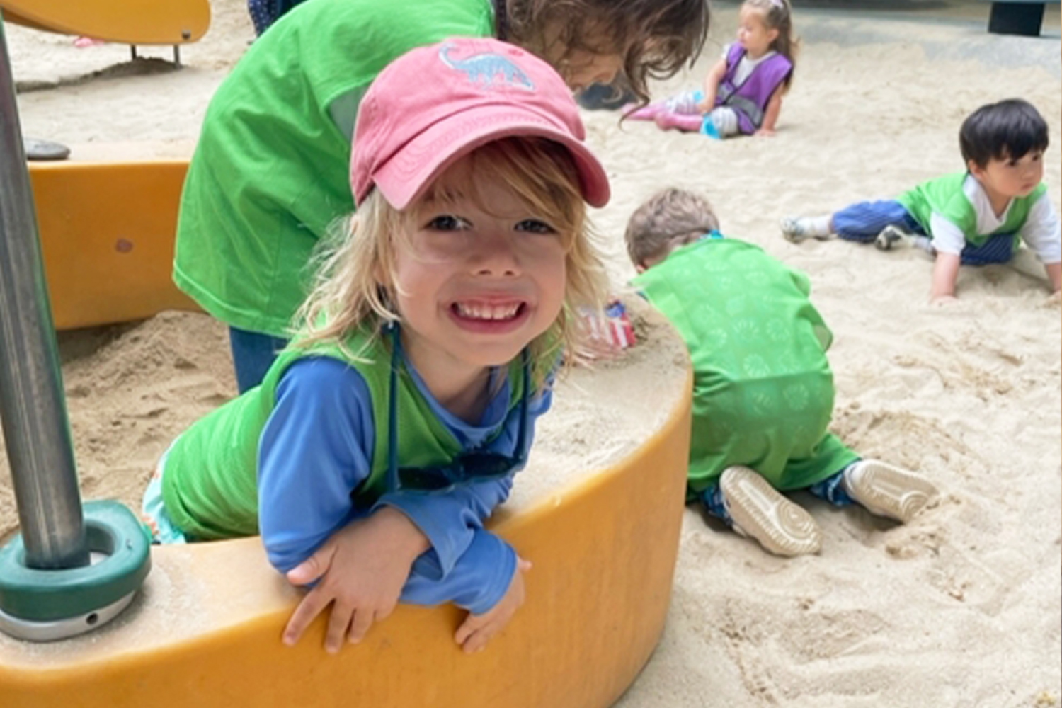 A student/camper smiling while playing at the playground