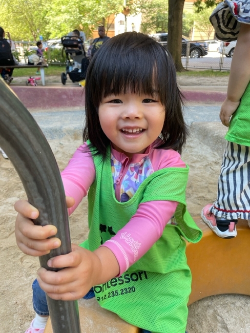 A student/camper smiling while playing at the playground
