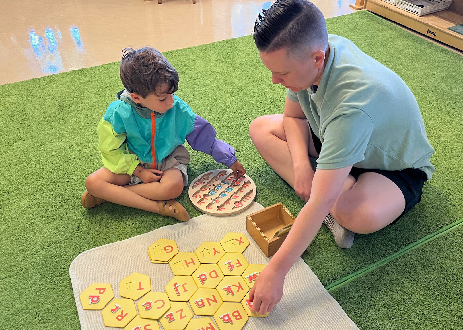 Teacher guiding student through a Upper-case lower-case letter activity in a Battery Park Montessori classroom