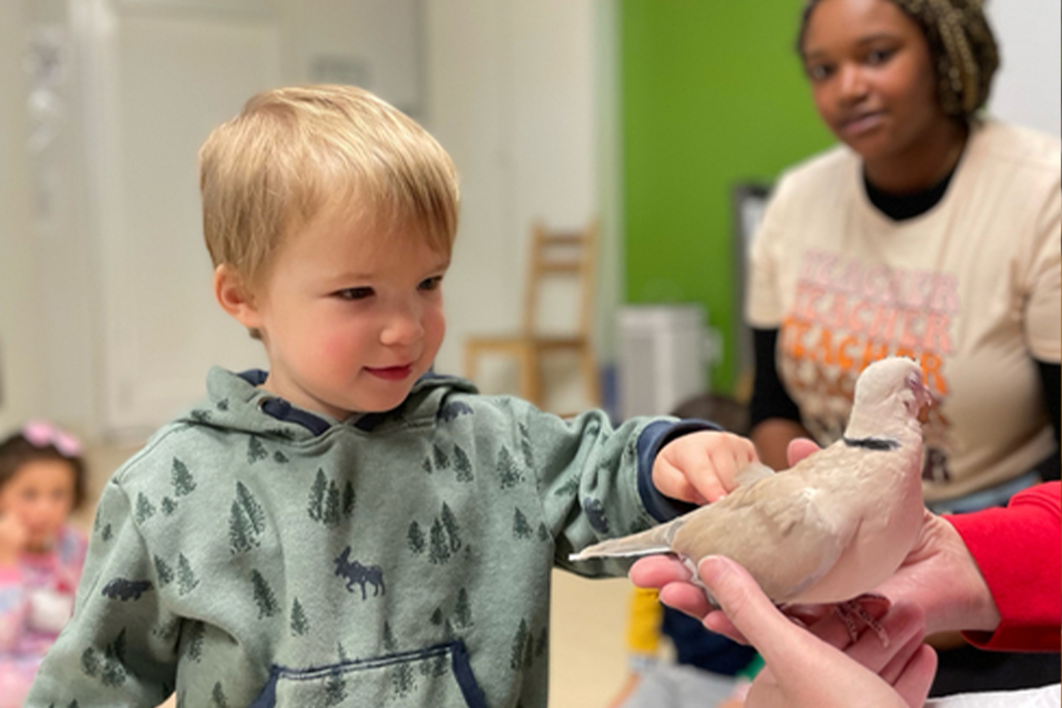 A Battery Park Montessori student pats a bird during an Art Farm visit as a teacher looks on