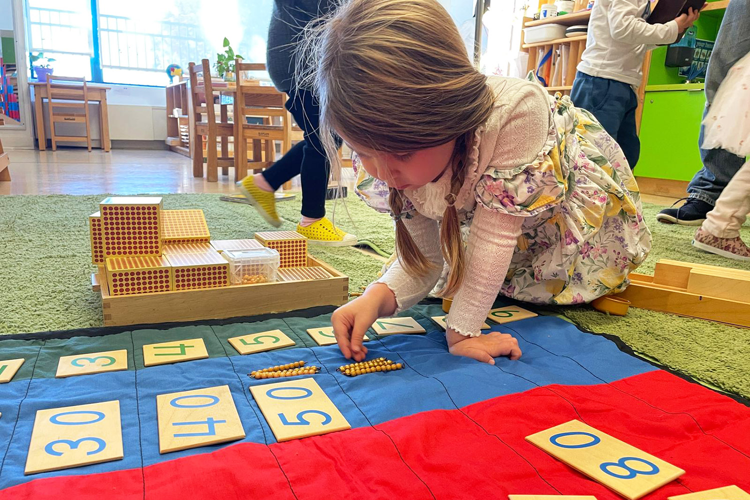 A Battery Park Montessori Casa student working on her tens board and counting to 100