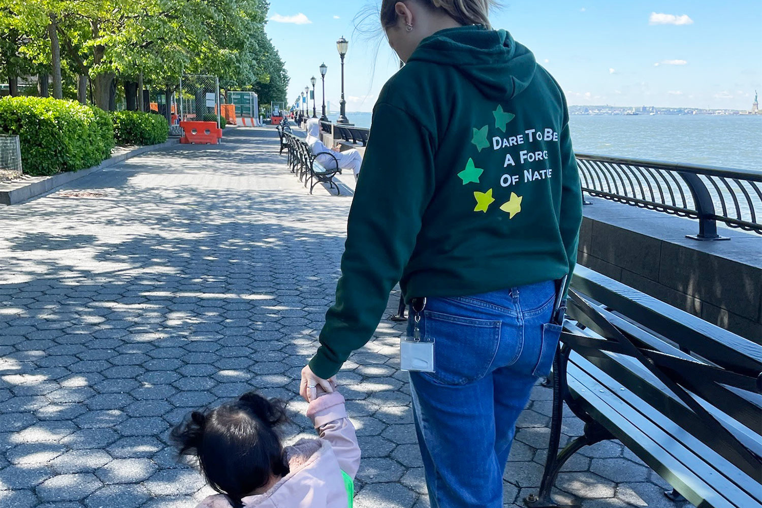 Teacher and student walking along the pathway of Battery Park City's waterfront next to the school