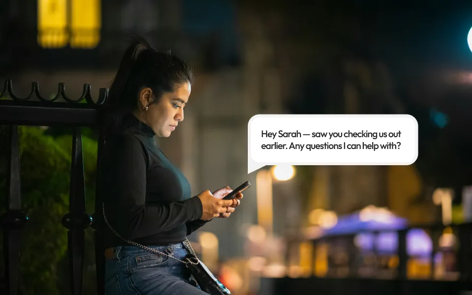 A woman on her phone with a text bubble coming out of her phone from a company.