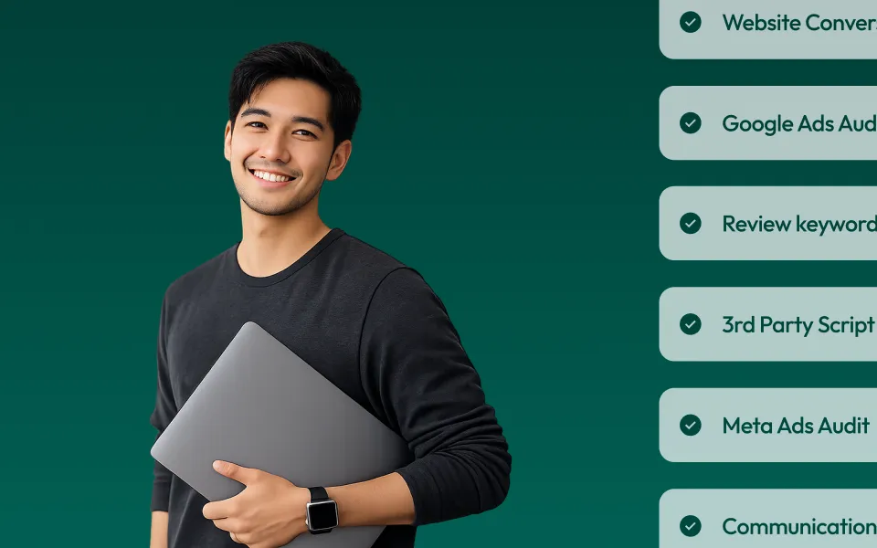 Smiling young man in a dark long-sleeve shirt holding a closed laptop against a green background.