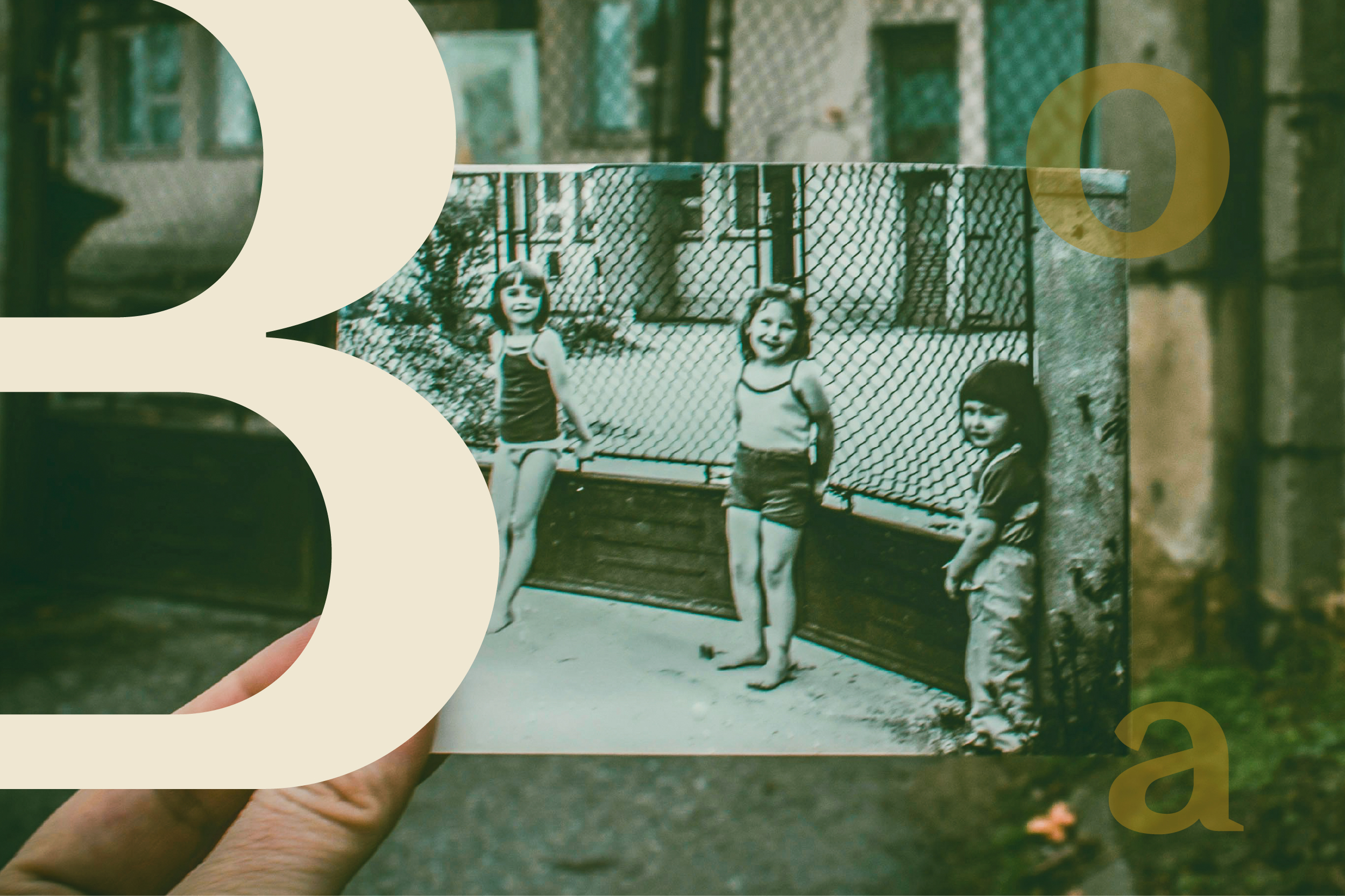 A hand holds a black and white photo of three children outdoors.