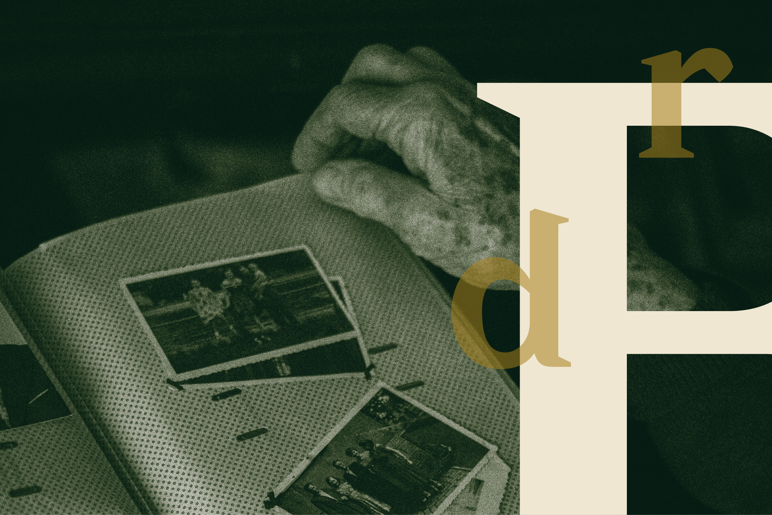 An aged hand rests on an open album holding black and white photos.