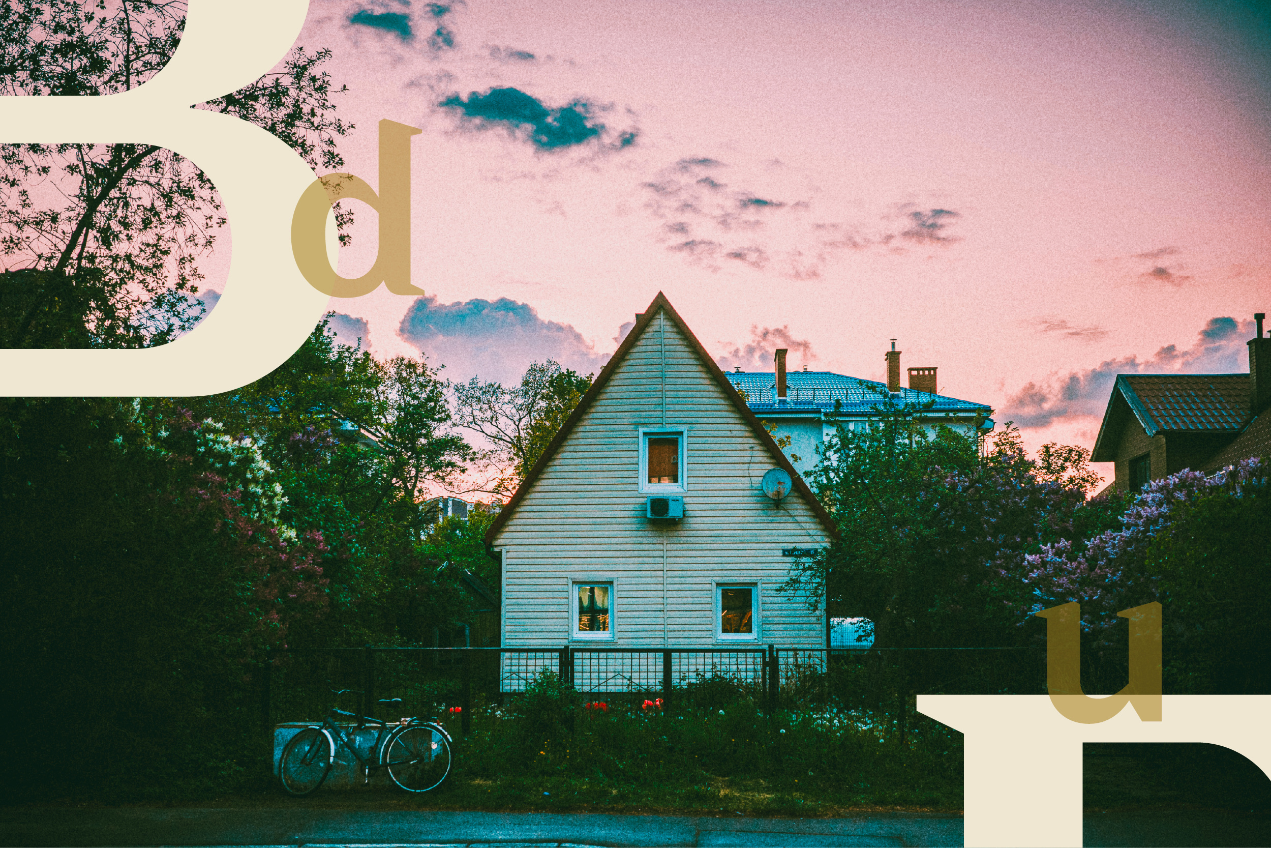 A small white house at dusk with bicycles parked by the fence.