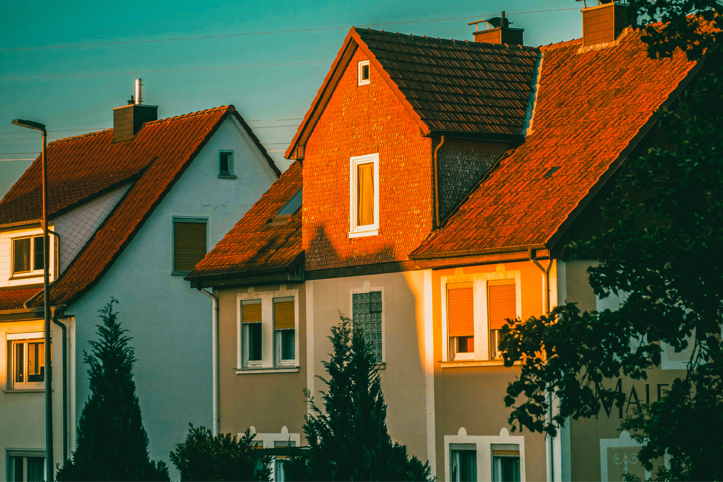 Suburban houses with red tile roofs lit by low evening sun.