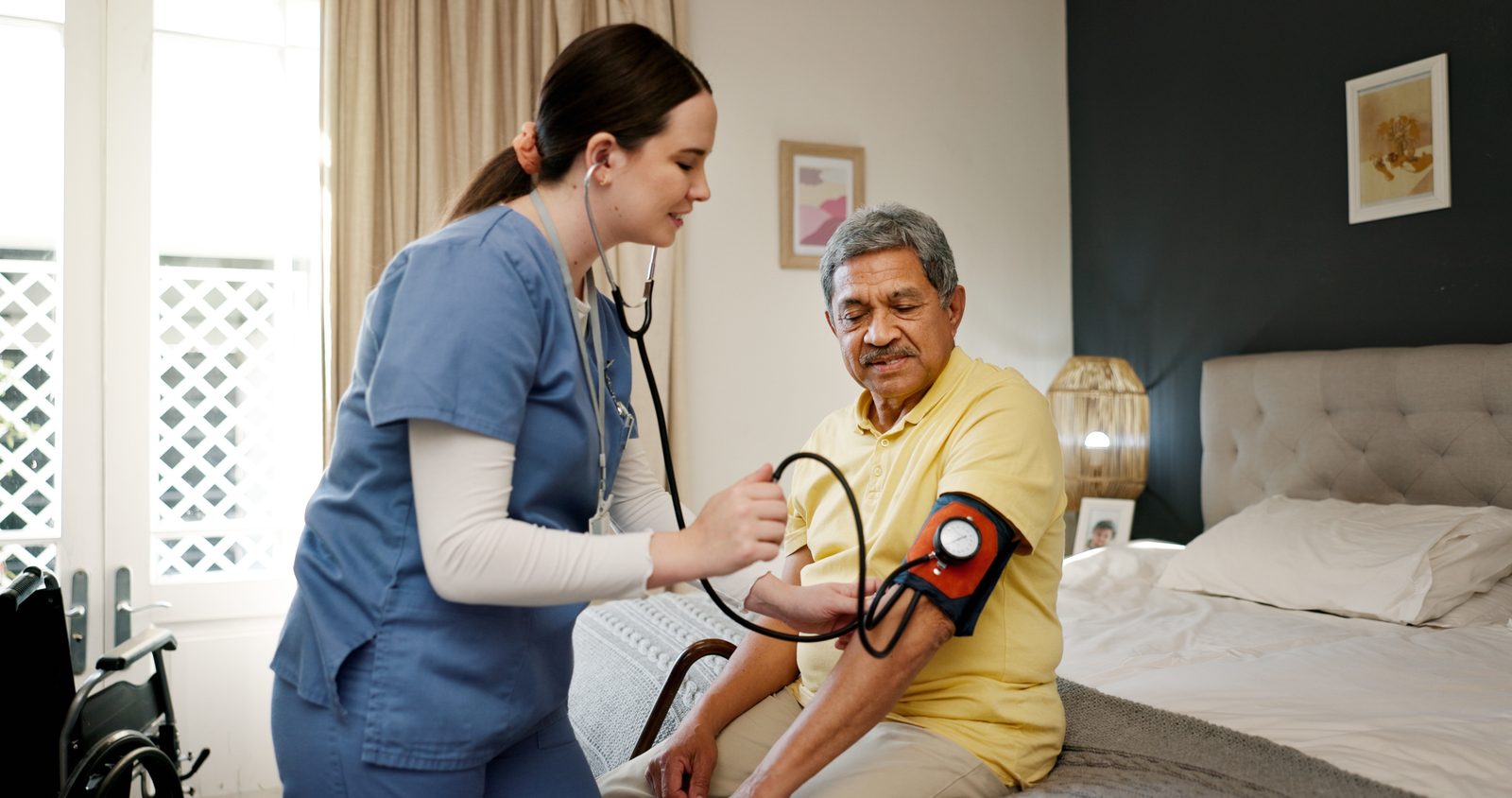 A nurse taking an older man's blood pressure in his bedroom