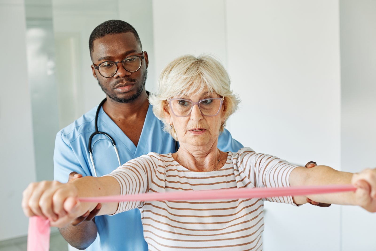 A physical therapist guiding an older woman through resistance band exercises