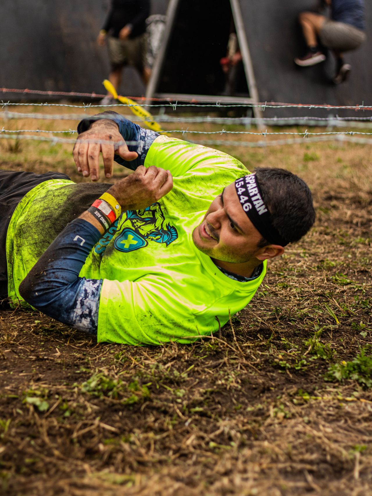An Access Home Health team member crawling under barbed wire at a Spartan race