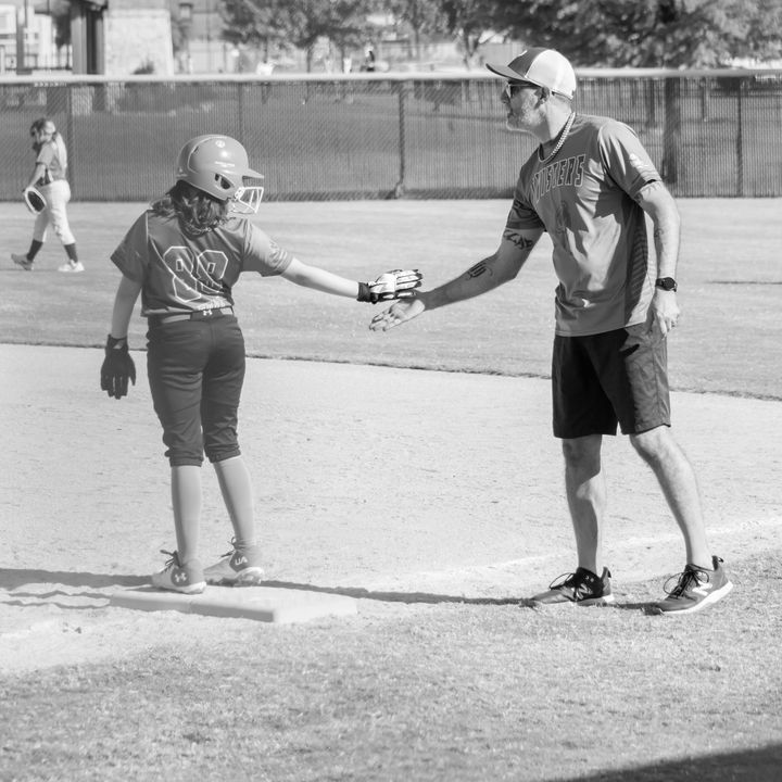 Jeff meeting a player at first base for a low five
