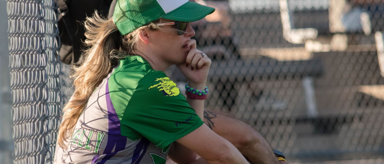 Kelly sitting against the dugout fence between innings