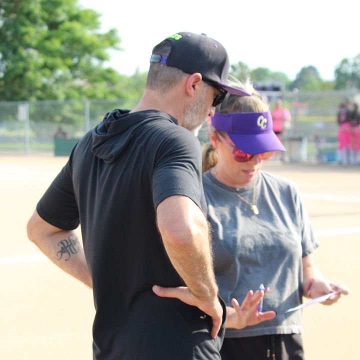 Kelly and Jeff talking over a lineup card during a game