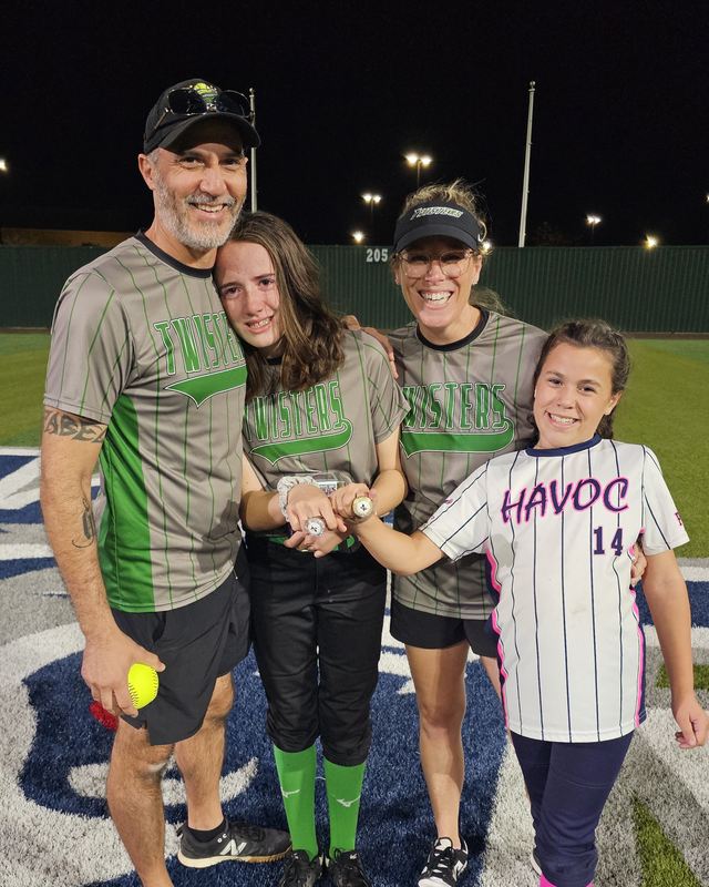 Kelly, Jeff and their two players on the field at night holding championship rings