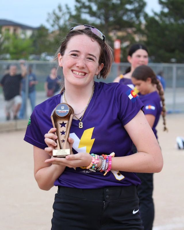 A player holding the Cherry Creek Little League 12U championship trophy