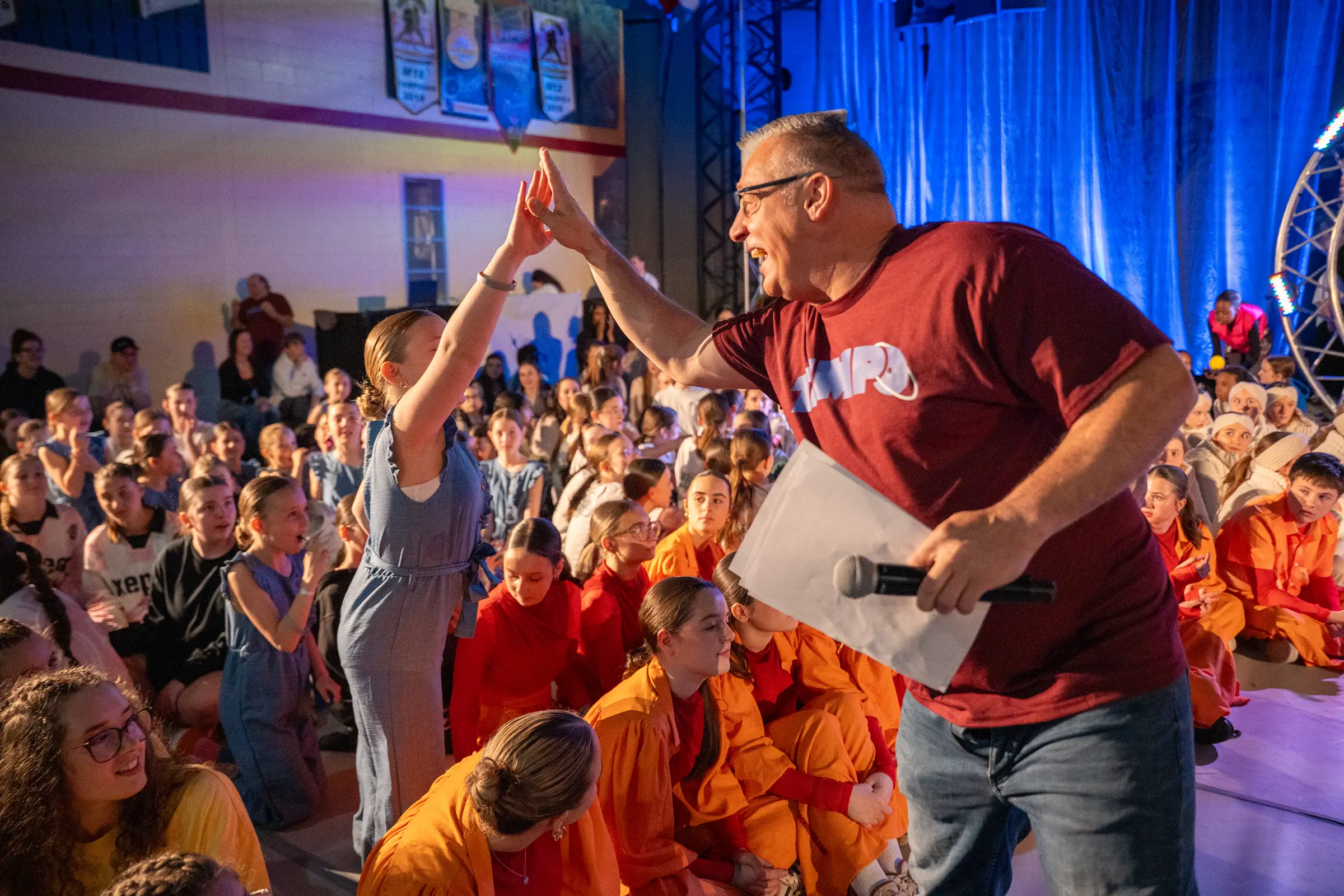 L'animateur tape dans la main d'une participante devant la foule au Championnat de danse Tempo 2026