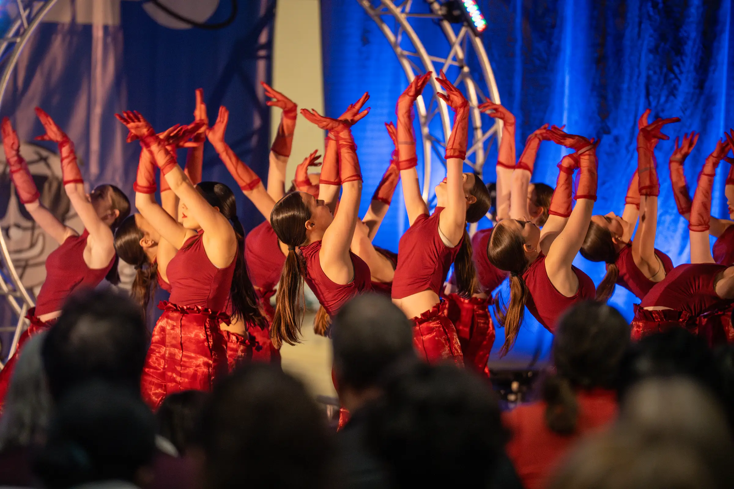 Une équipe en costumes rouges lève les bras en finale de sa chorégraphie au Championnat de danse Tempo 2026