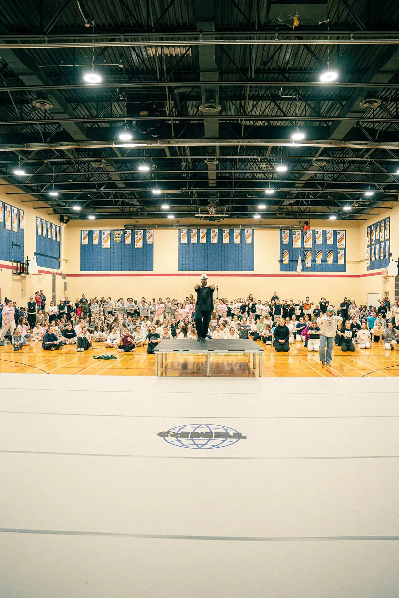 Le gymnase rempli de participants assis pendant une prise de parole au Championnat de danse Tempo 2024