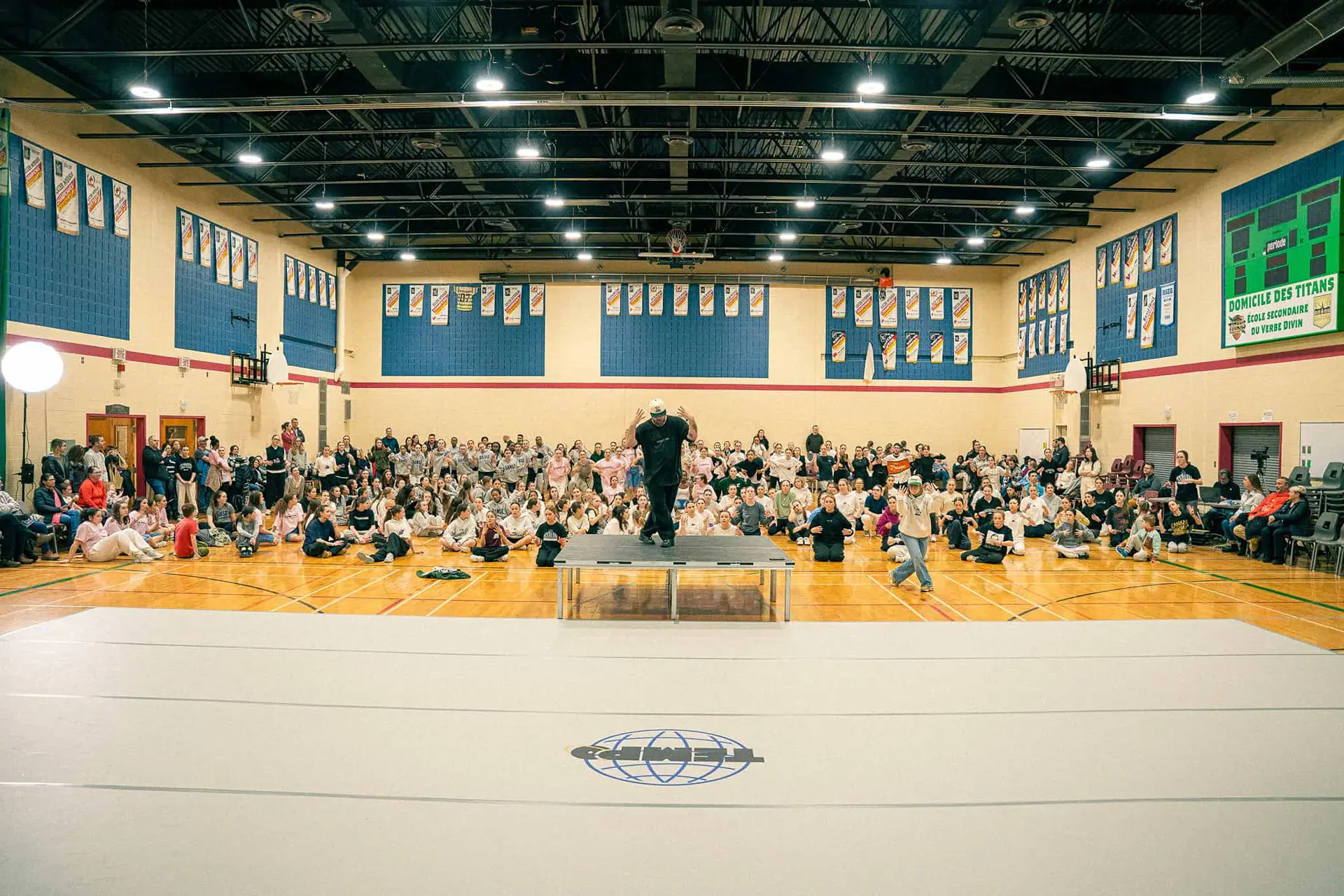 Le gymnase rempli de participants assis pendant une prise de parole au Championnat de danse Tempo