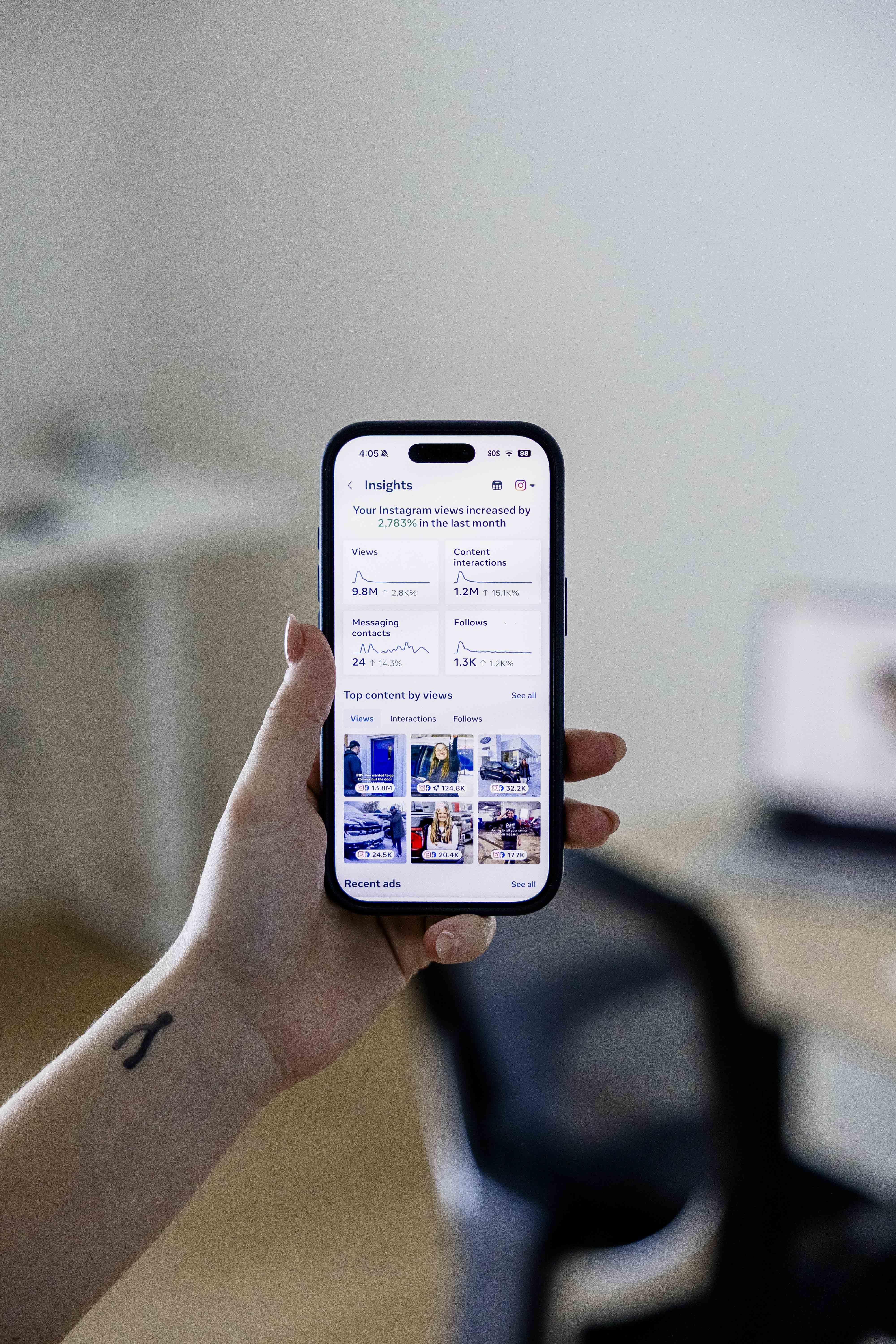 Hand holding a smartphone displaying Instagram Insights analytics with views and content interaction metrics