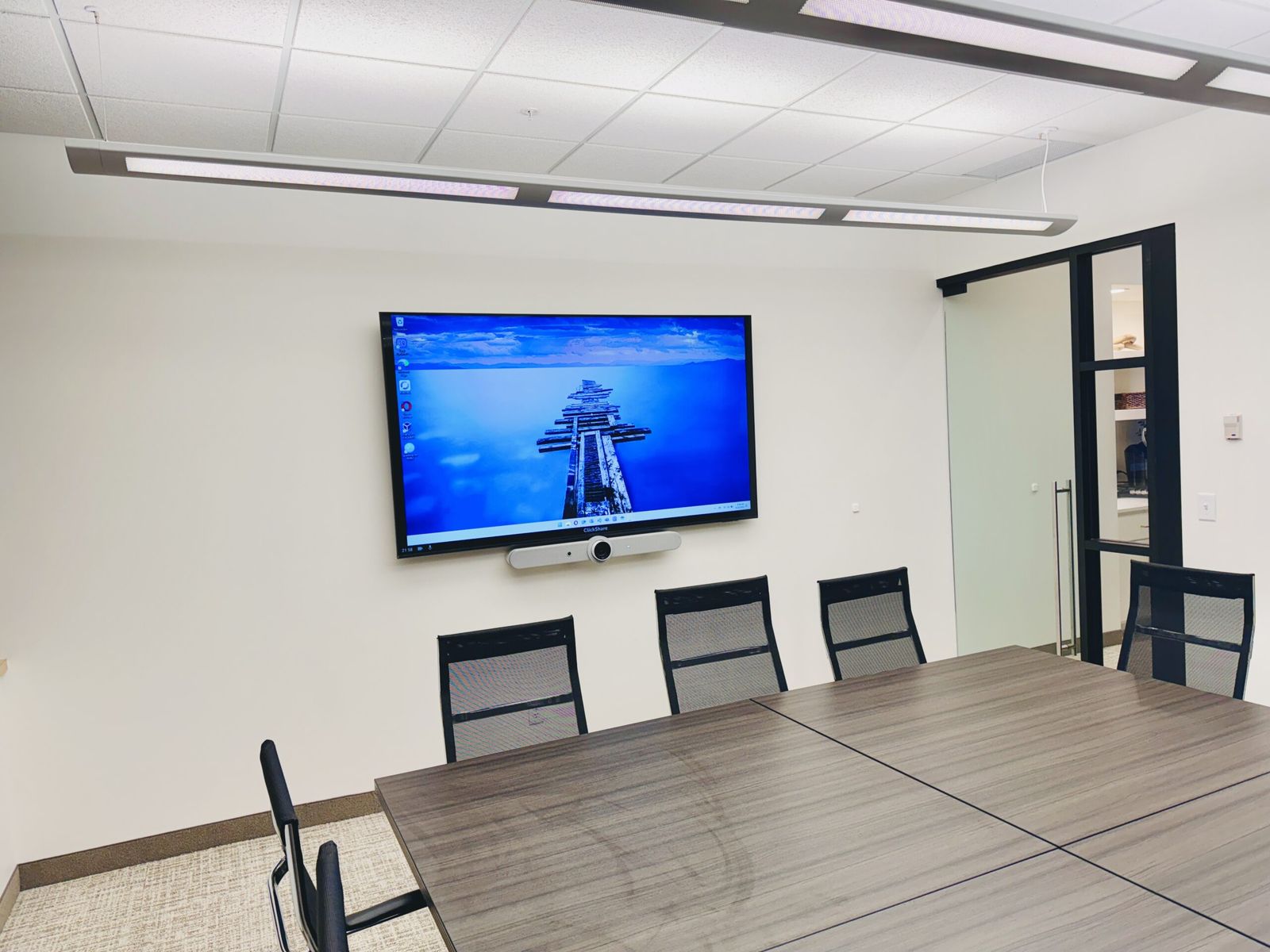 Conference room AV installation with wall-mounted display, video bar, and meeting table