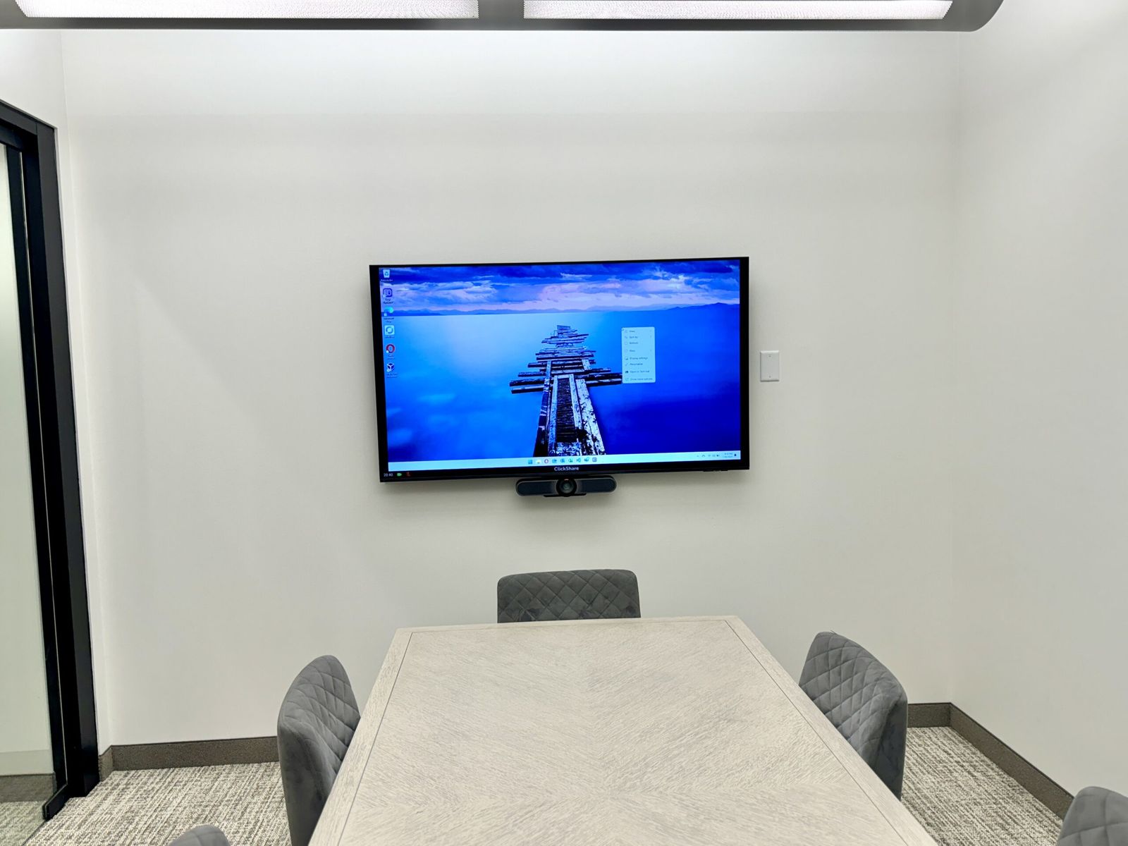 Small meeting room with wall-mounted display and video conferencing camera