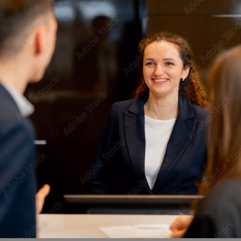 NINE Private Investment Office receptionist in a dark blazer smiling at clients over a desk