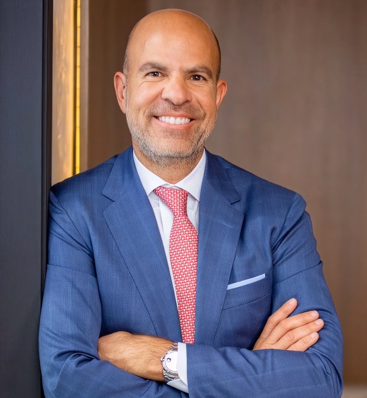NINE Private Investment Office founder Harvey Hernandez smiling in a blue suit and red tie