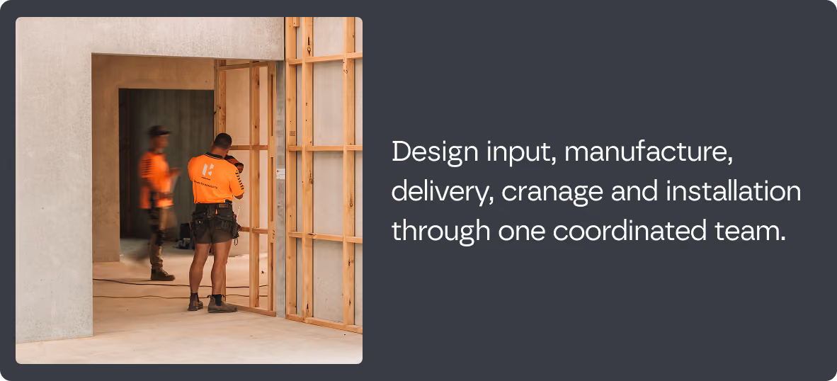 Two construction workers inside a building under construction, one facing a wooden frame wall and the other walking, accompanied by text about design input, manufacture, delivery, cranage, and installation by one coordinated team.