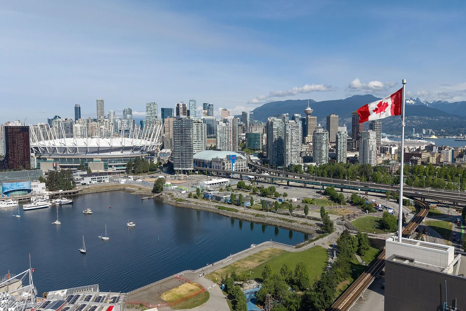 Vancouver skyline, False Creek and the North Shore mountains, with a Canadian flag in the foreground