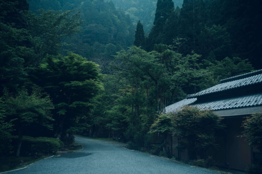 The approach beside Miyamasou, with a tiled roof and wooded mountain landscape.