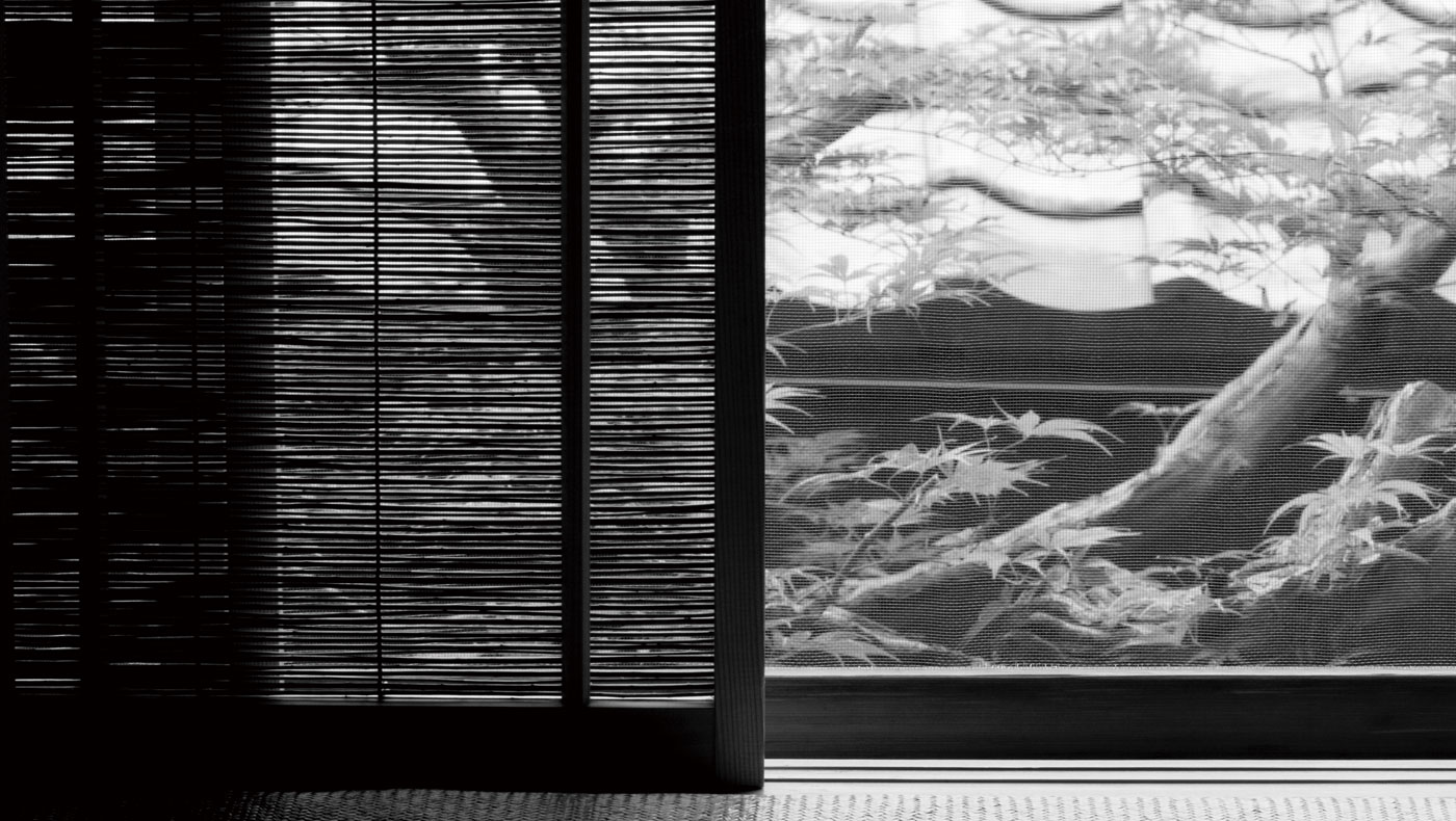 Black-and-white architectural detail of a woven blind, window frame and foliage at Kodaiji Wakuden.